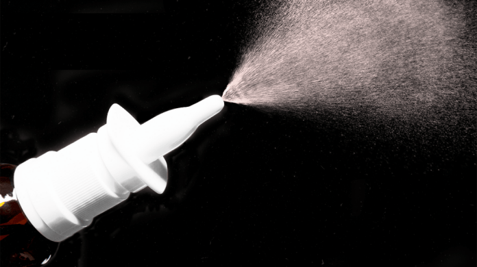 nozzle of nasal spray spraying particles on black background