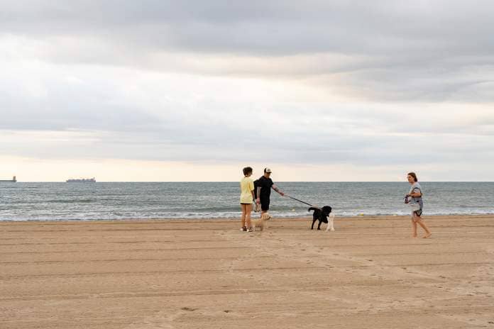 Couple walking dogs in Pinedo Beach, Valencia, Spain