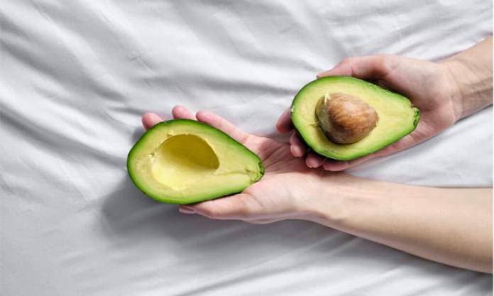 Woman's hands holding a cut avocado
