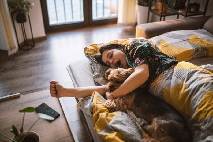 Young woman and her dog waking up in the morning.