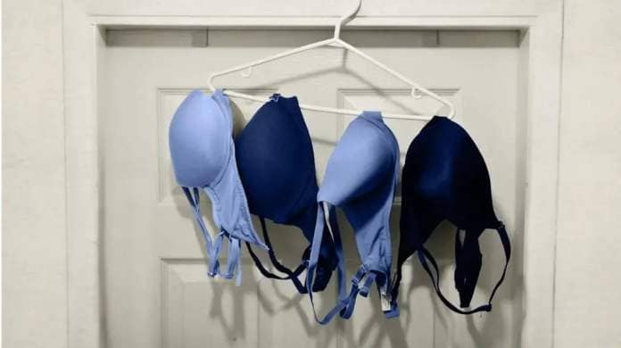 Four pairs of bras hanging on a hanger hung on a door frame.