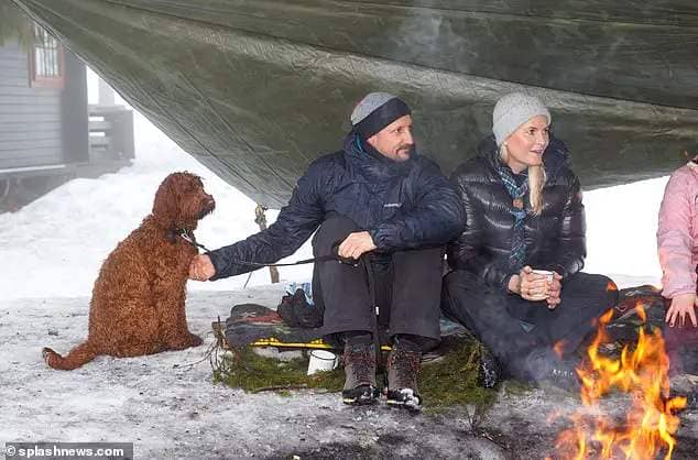 Princess Mette-Marit of Norway was chic in a padded navy jacket while her husband Prince Haakon stroked their dog Molly by a campfire