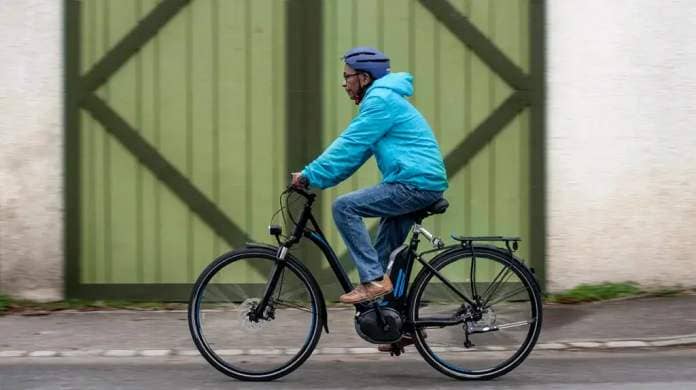 A man wearing a helmet while riding a bicycle on a city street