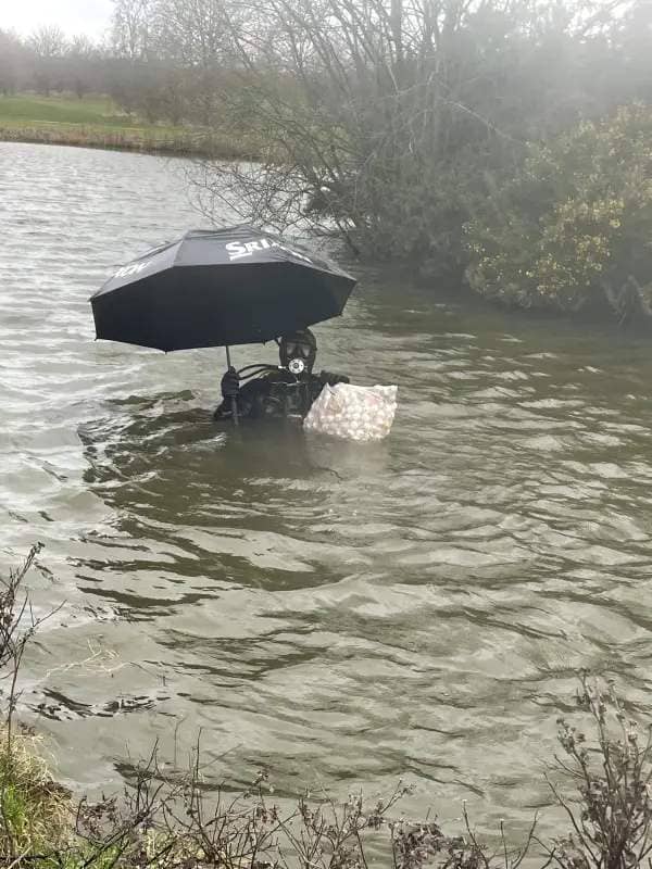 A golf ball diver posing with an umbrella found at the bottom of the pond (Collect/PA Real Life).