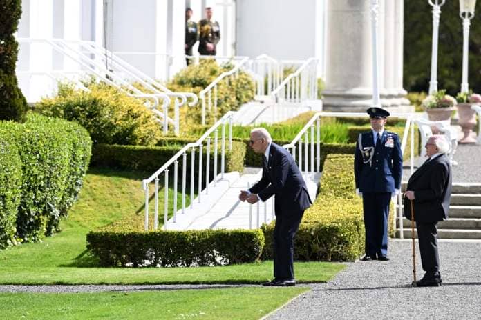 US President Joe Biden (L) calls on a dog belonging to Irish President Michael D Higgins (R) and his wife Sabina Higgins in the grounds of the Irish President's official residence.