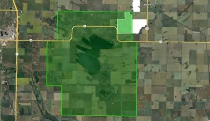 A satellite image shows a green shape extending a kilometre around the boundary of Frank Lake. In the green image's northeast corner lies a significant portion of the solar project. 