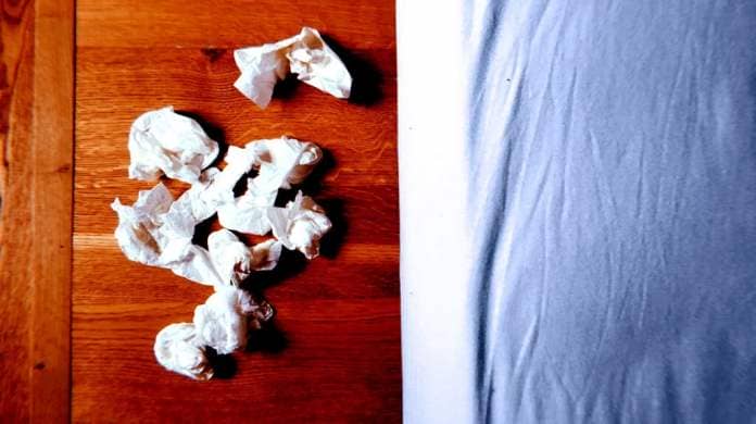 A close up of crumpled used tissues after a cold or flu on the floor