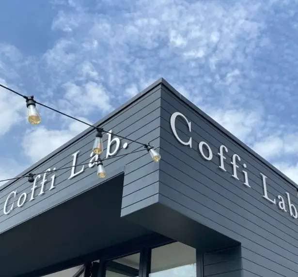 Signage and string lights at Coffi Lab against the backdrop of a blue sky