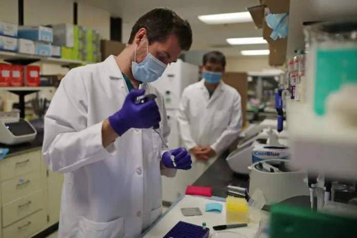 A lab technician prepares a solution that will be used to process coronavirus test samples at a molecular diagnostics laboratory.