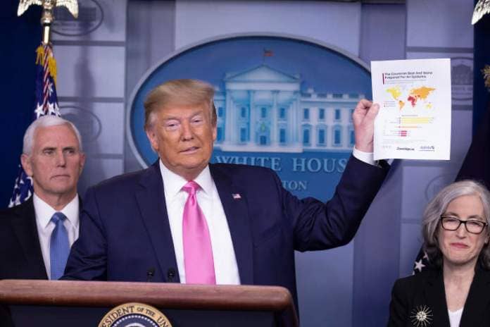 Then-President Trump holds up a sheet of paper with graphics at a news conference with members of the coronavirus task force, including Vice President Mike Pence in 2020.