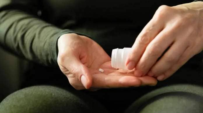 A pill from a bottle in a man's hand