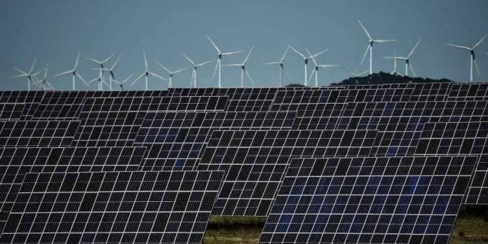 This photograph shows photovoltaic solar panels and windmills in the background around the Spanish Navarre town of Milagro on April 5, 2023.