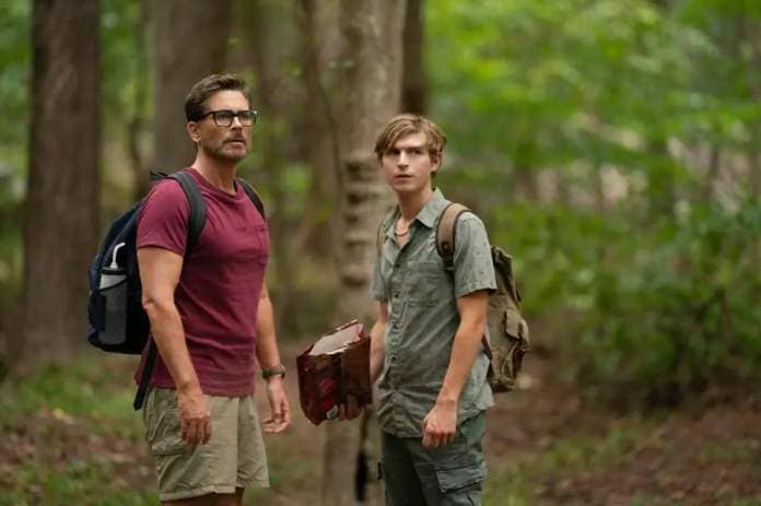 a father and son search the woods for a lost dog in a scene from dog gone, a good housekeeping pick for bet kids&#39; movies 2023