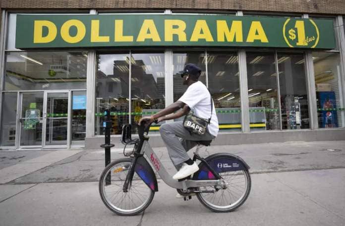A person cycles past a Dollarama store in Montreal, Wednesday, June 7, 2023. THE CANADIAN PRESS/Christinne Muschi
