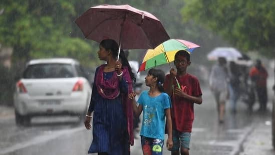 Commuters out in the rain in Sector 12, Noida.(Sunil Ghosh/ Hindustan Times)