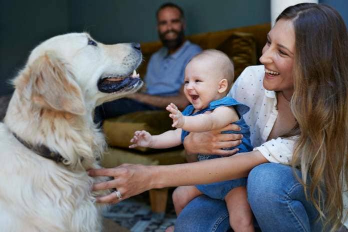 woman holding baby and petting a dog