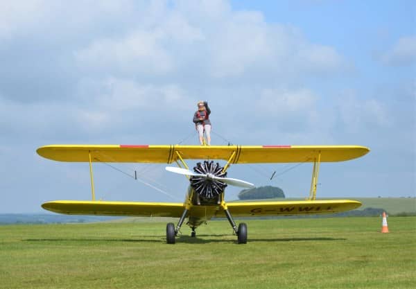 Cherry Lorberg stood on top of yellow plane, waving at camera