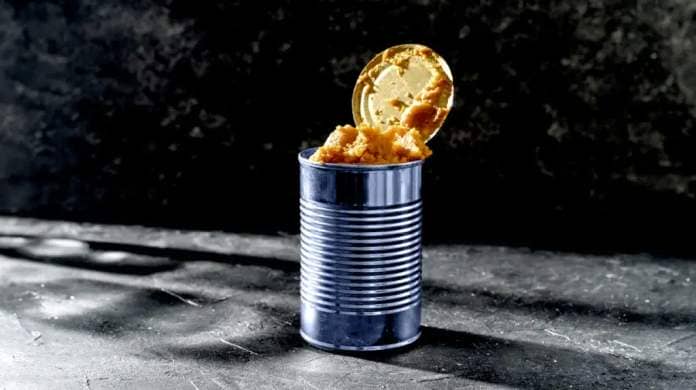 An open can of food sits on the ground