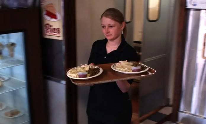 Server Indre Doyle brings out two platters of chicken and dumplings for customers at Doyle's Diner on March 10, 2005, in Selbyville, Delaware.