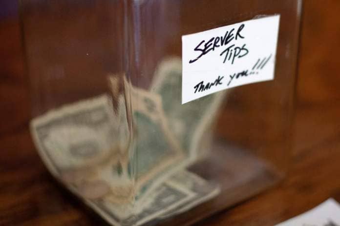 A cash tip jar stands on the counter at Bellevue Bistro in Bellevue, Kentucky, on Wednesday, Feb. 3, 2021. The bistro was among local restaurants to receive a $1,000-plus tip on an order in what was called the "Crosstown tip-off."