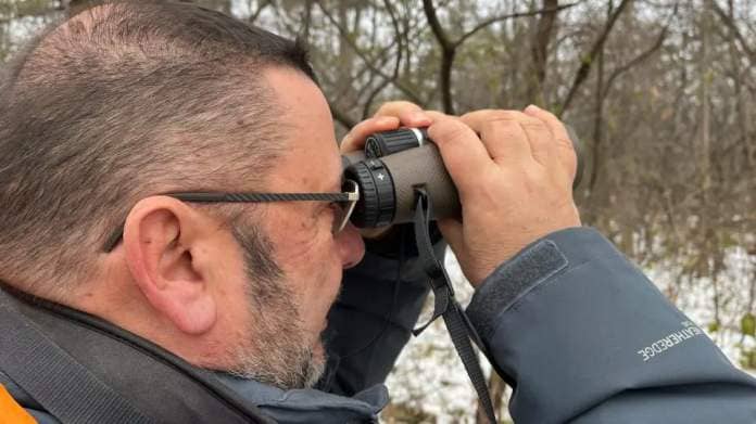 Bernie Ladouceur peers through binoculars at Mud Lake Dec. 12, 2023, a few days before the 2023 edition of the Christmas Bird Count he helps with.