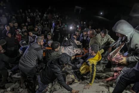 An injured man is rescued as residents and civil defense teams conduct search and rescue operation under the rubbles after an Israeli attack on a building in Deir al-Balah, Gaza.