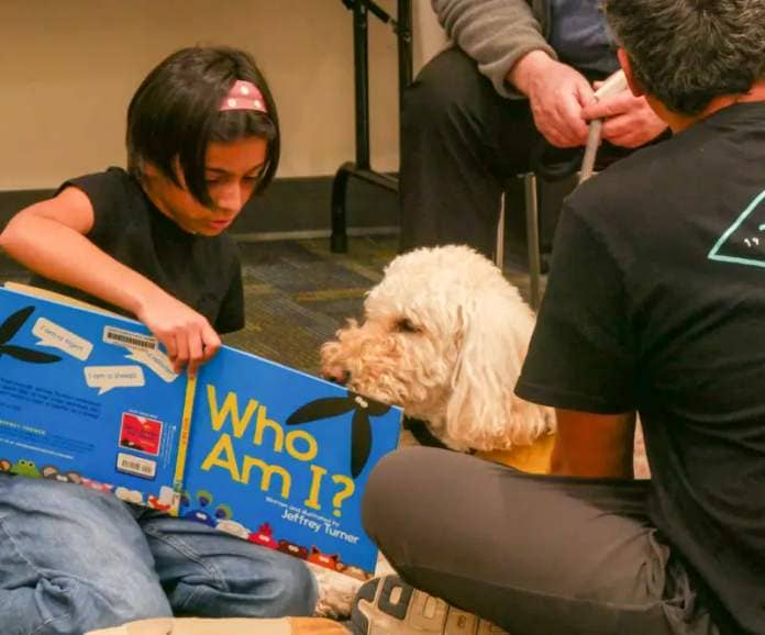 Children in grades K-6 read books to certified therapy dogs to practice their reading skills in a judgmental free zone at the Valencia Library community room on Thursday evening. Katherine Quezada