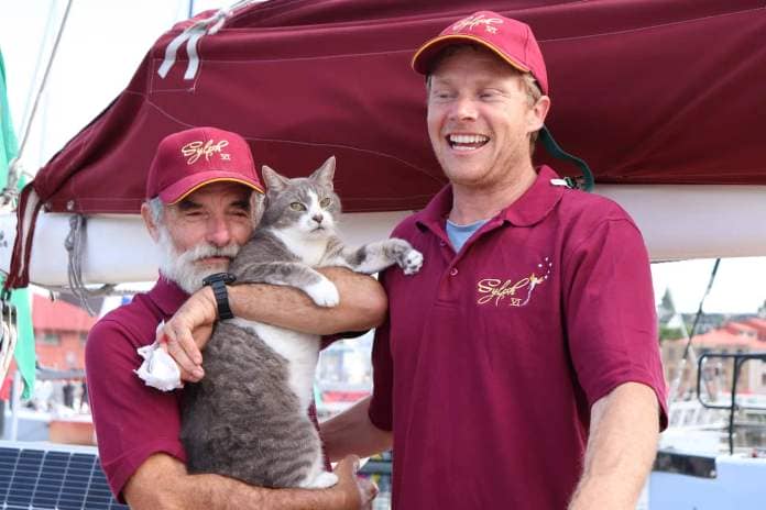 Two men in red T-shirts, with one holding the cat.