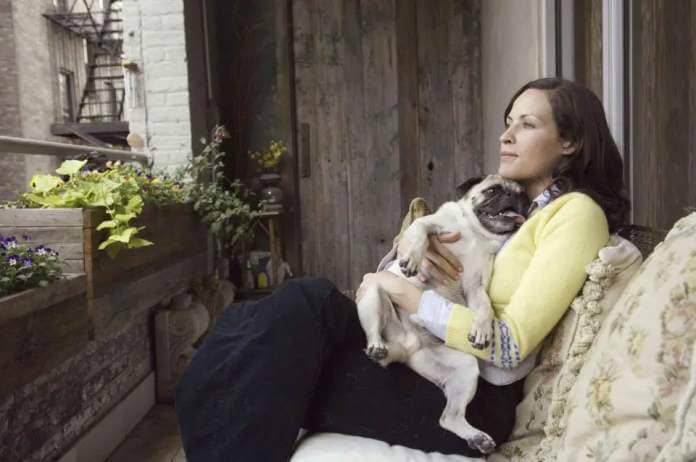 Dennis Kleinman/Getty Images Woman cuddles dog on porch.