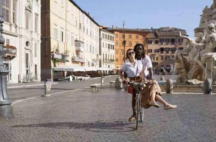 beautiful biracial couple riding bicycle in deserted piazza navona, rome, italy, used to illustrate a story about cute nicknames for boyfriends