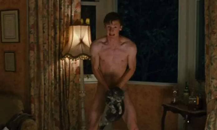 A naked man (Timothy Cavendish) stands in a hotel room with his back to a darkened window, a look of embarrassment and alarm on his face, and holds a limp grey (CG-rendered cat) over his groin to hide his genitals in Cloud Atlas