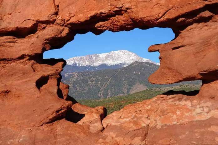 View of Pikes peak through the hole in the Siamese Twins red rock formation in the Garden of the Gods park in Colorado Springs, Colorado, United States