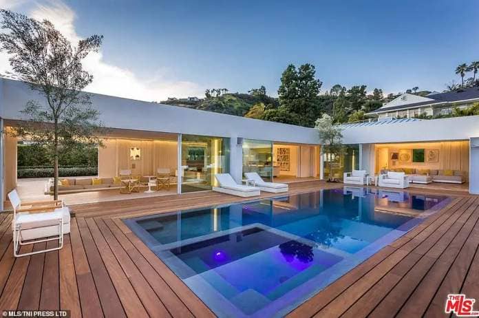 Floor-to-ceiling glass walls on all sides of the property offer views across the external wood-decked garden and outdoor swimming pool