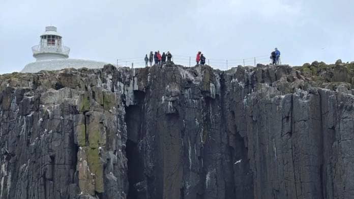 People standing on the edge of Inner Farne next to the lighthouse 