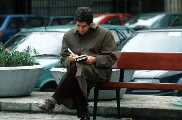 Charlie Bird writes up his notes while sitting on a bench outside the Dáil in 1991. Picture RollingNews.ie