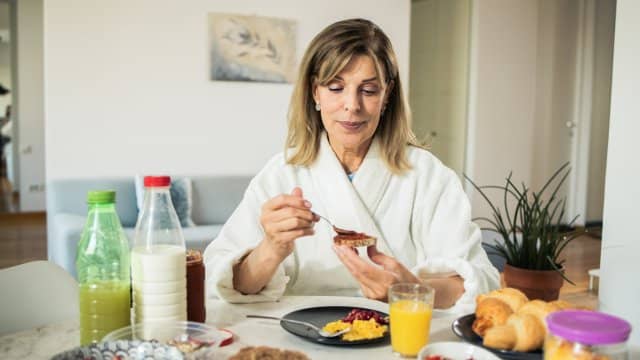 Middle-aged woman is having breakfast at home