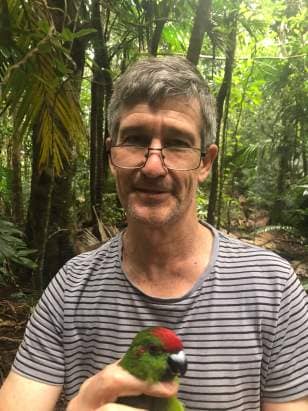 1. Researcher robert heinsohn with a norfolk island green parrot
