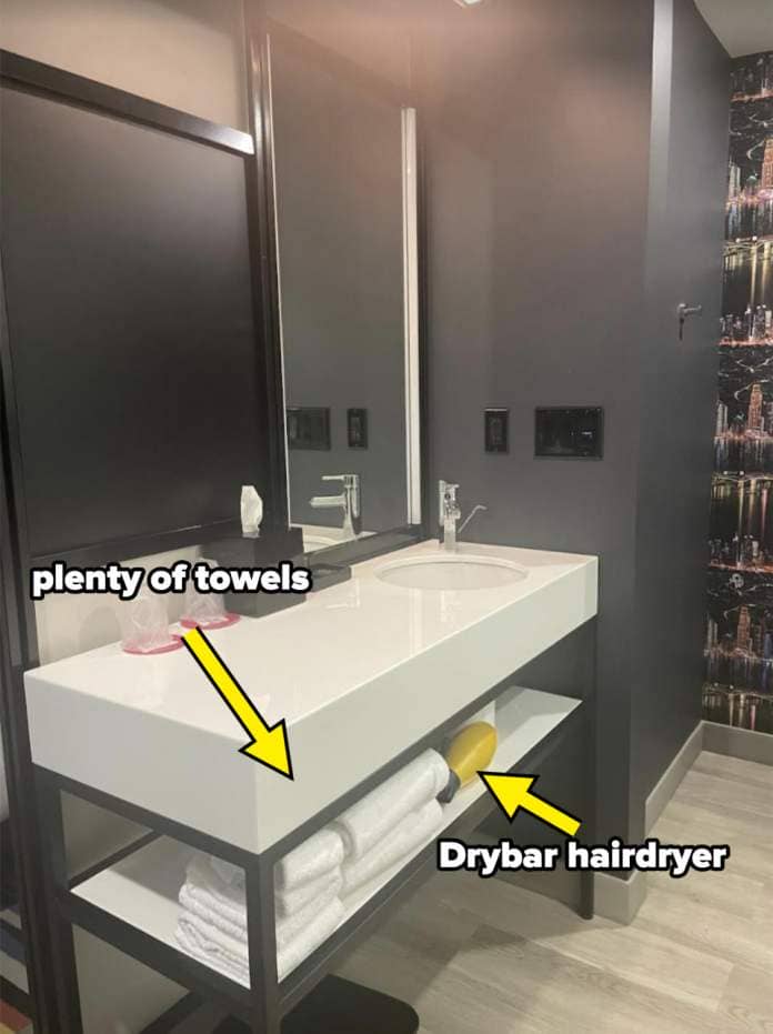 Modern hotel bathroom with a sink, mirror, and towels on a shelf