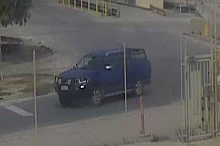 CCTV image of a blue ute on the road next to a tall wire fence